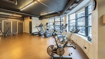 A gym with cardio equipment, a physiotherapy room, and large windows.
