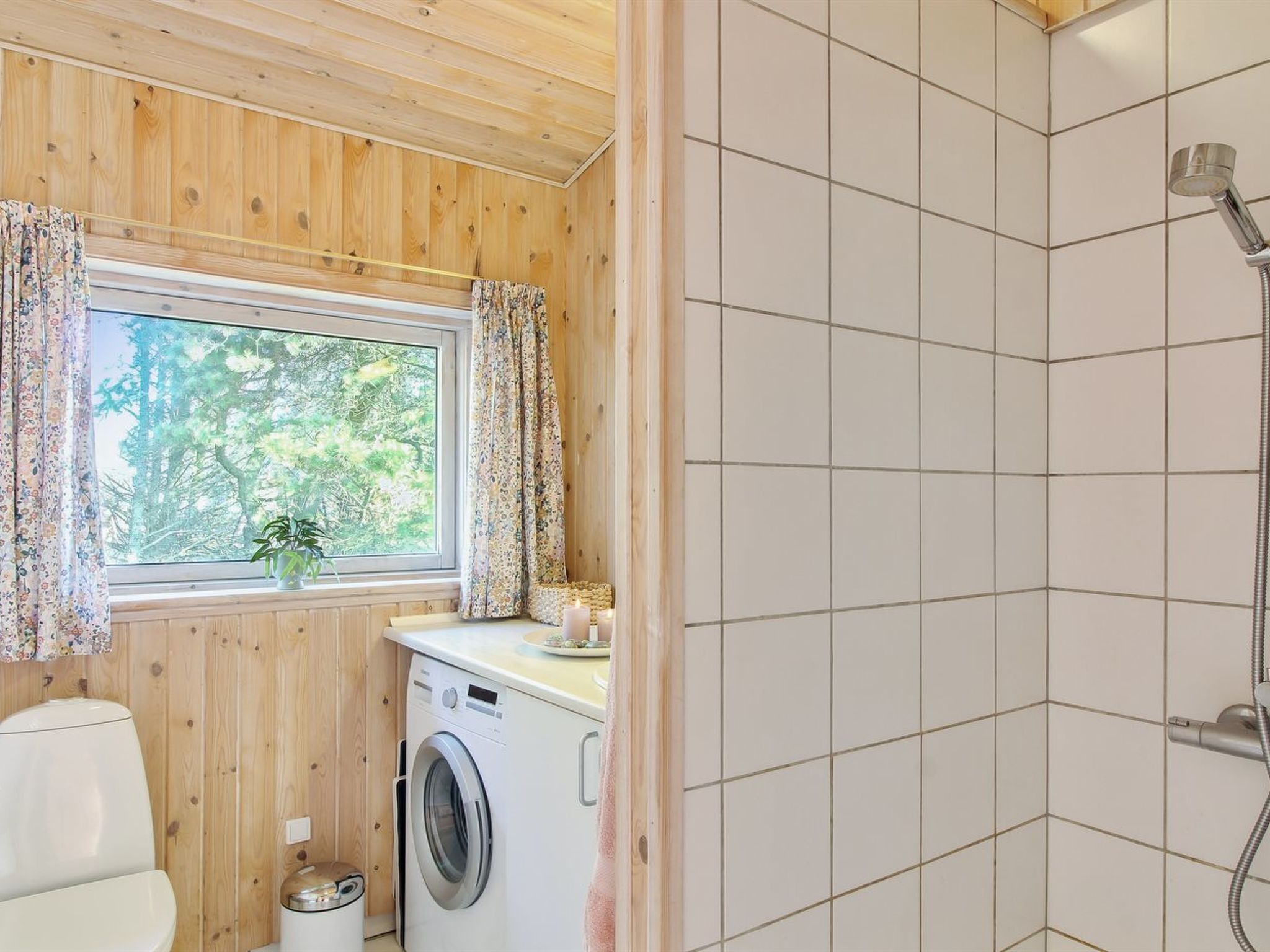 Baño pequeño con lavadora, inodoro y ducha.