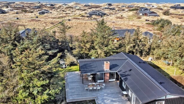 A modern house with a deck, surrounded by a natural landscape and other houses. - "Tuukka" - 350m from the sea by Interhome (Løkken)