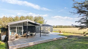 A modern cabin with a deck, large windows, and a view of the surrounding landscape. - "Tuukka" - 350m from the sea by Interhome (Løkken)