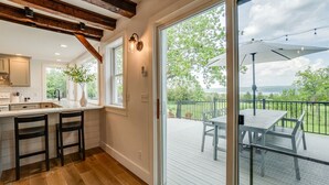 A modern kitchen with wooden beams, a large sliding glass door leading to an outdoor deck with a table and chairs.