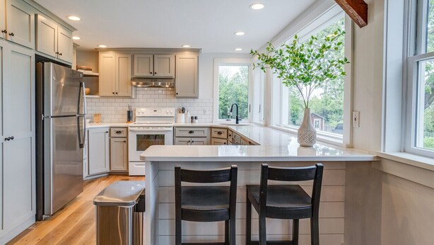 A modern kitchen with white cabinets, stainless steel appliances, and a large island with bar stools.