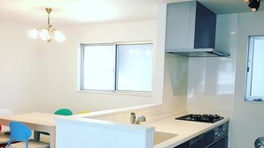 Une cuisine moderne dotée d’un îlot central, d’une cuisinière à gaz et d’un four encastré. Une fenêtre se trouve au-dessus de l’évier et un luminaire est fixé au plafond.