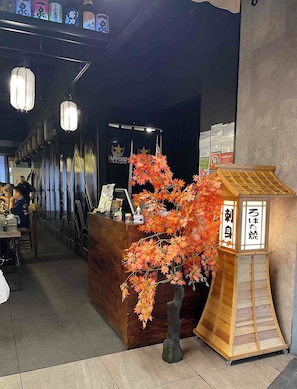 A reception area with a wooden desk, a decorative tree, and a sign with Japanese characters.