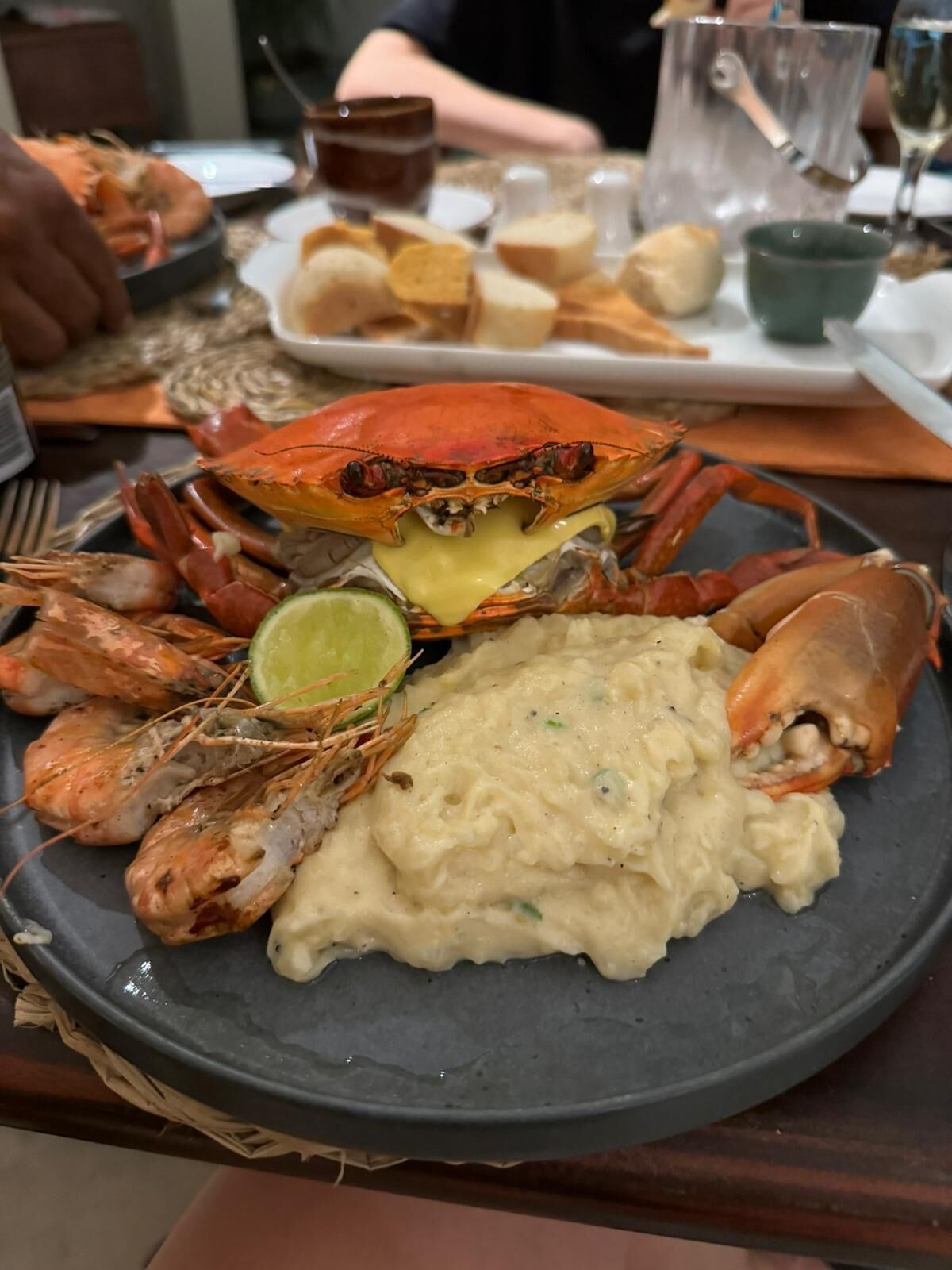 En fiskeplatter med krabbe, rejer og en stor portion mos, serveret på en mørk tallerken.
