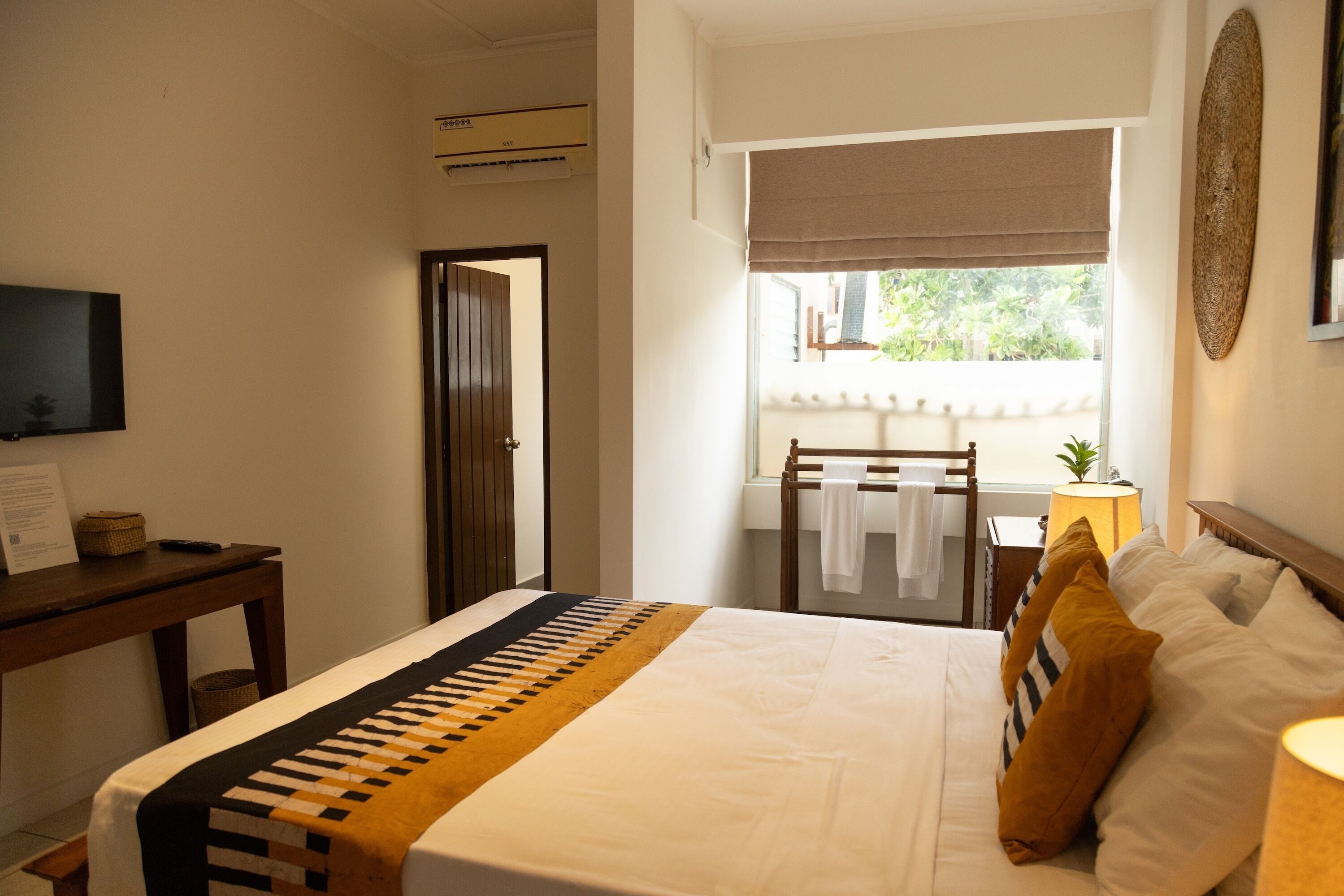 Une chambre à coucher comprenant un lit, un bureau, une chaise, une fenêtre avec vue et un téléviseur fixé au mur.