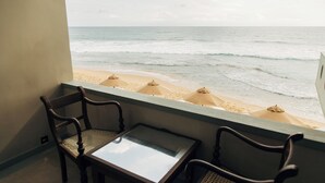 Un balcó amb vista a la platja, amb dues cadires de fusta i una taula petita.