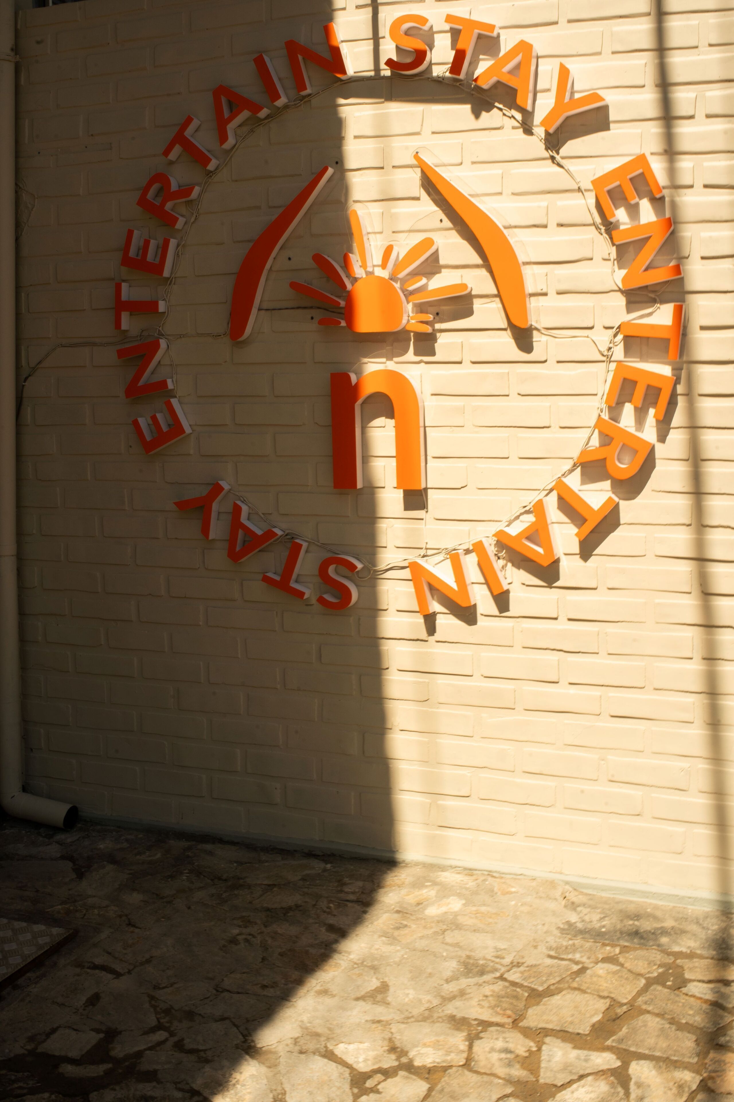 Un mur sur lequel est affiché un panneau avec l’inscription « ENTERTAIN STAY ENTERTAIN » en lettres orange.