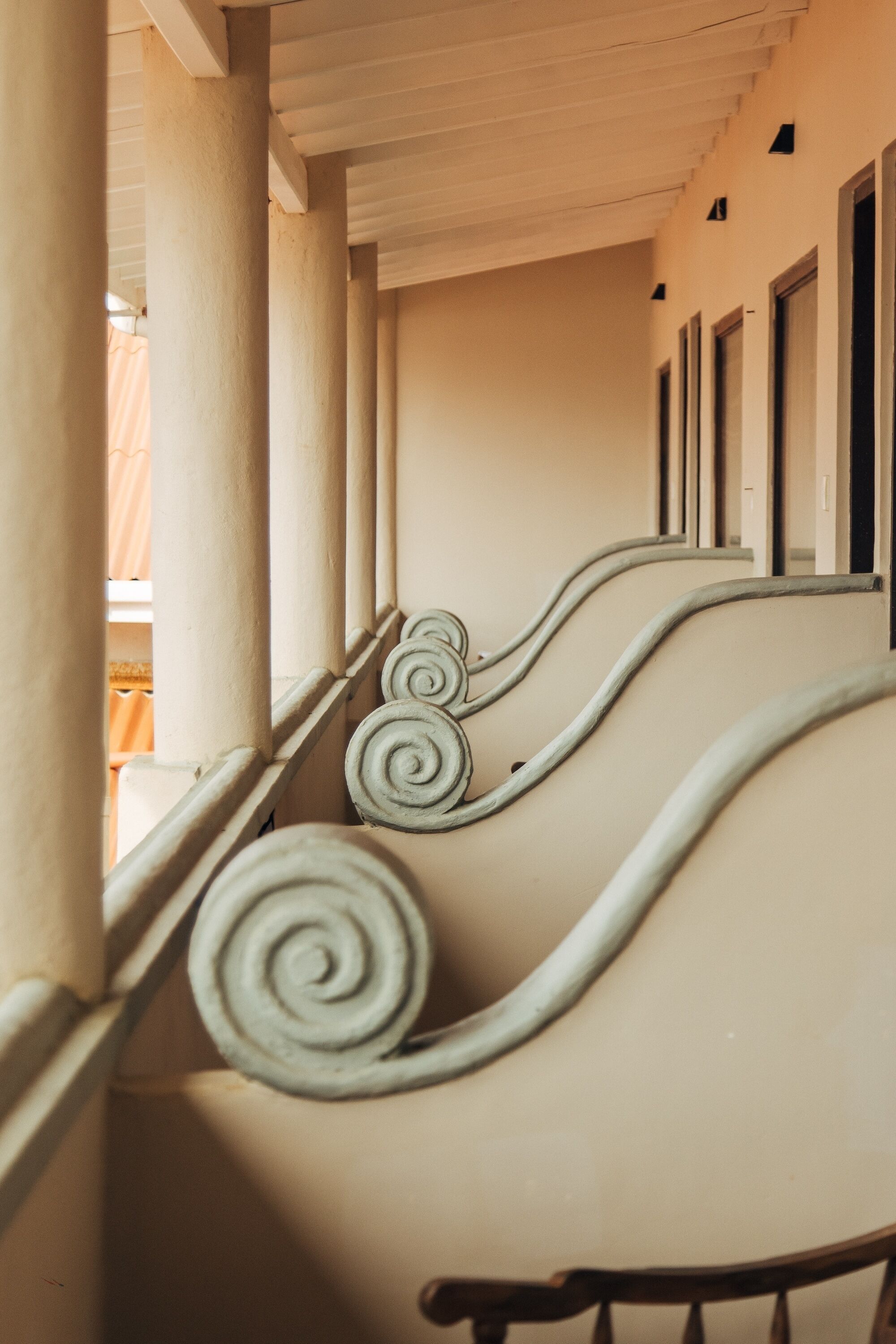 A corridor with columns and a ceiling with a series of windows.