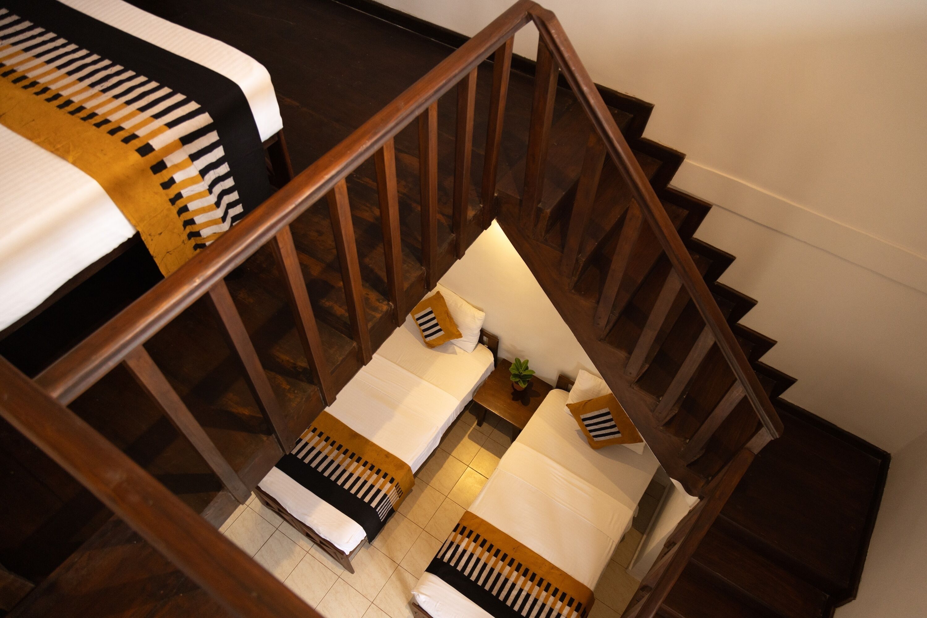 A staircase leading to a room with two beds, each with a striped bedspread and a pillow with a striped pillowcase.