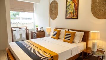 A neatly arranged bedroom with a bed, bedside lamps, a bedside table, and a window with a view.