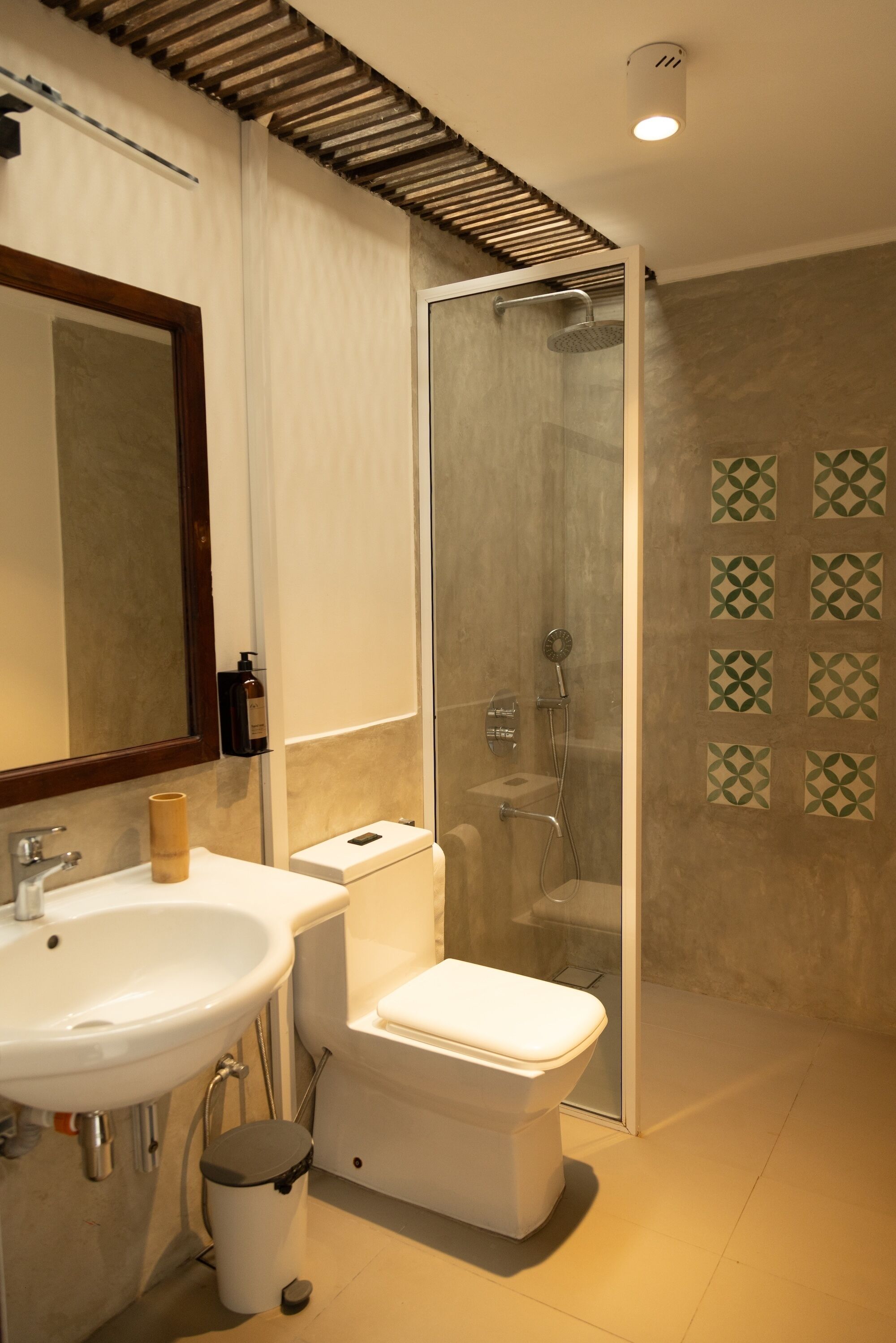 Un baño moderno con lavamanos blanco, inodoro y ducha con mampara de vidrio.