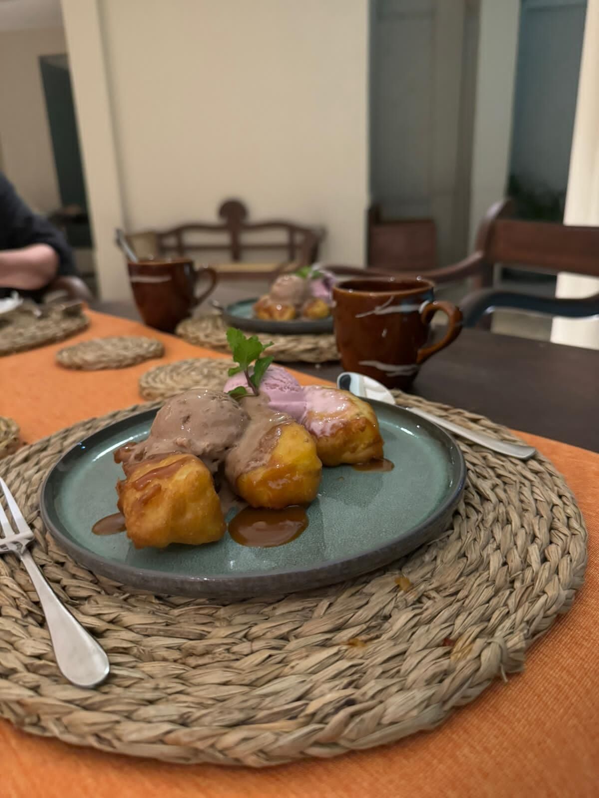 A dining table with a plate of food, a cup, and a fork.