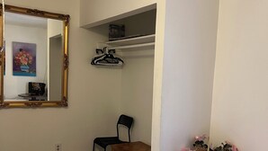 A bedroom with a bed, a desk with a chair, a mirror, a shelf with a box, and a small table with flowers. - Central, 3 bed-rooms, 2 showers, 5 mins airport, 10 mins strip/convention center (Las Vegas)