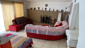 A bedroom with a curved bed, a red sofa, a red ottoman, a fireplace, and a window with blinds. - Central, 3 bed-rooms, 2 showers, 5 mins airport, 10 mins strip/convention center (Las Vegas)