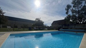 Ein rechteckiger Pool mit klarem, blauem Wasser, umgeben von einer gefliesten Liegefläche.