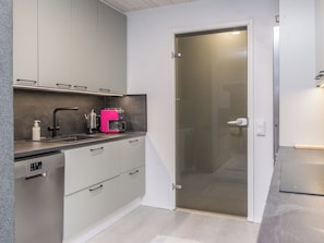 A modern kitchen with grey cabinets, a coffee machine, and a dishwasher. - Käkikello by Interhome (Mikkeli)