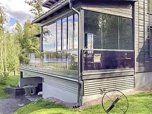 A modern house with a large glass window, a covered porch, and a view of a lake. - Käkikello by Interhome (Mikkeli)