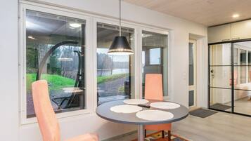 Een moderne eethoek met een ronde tafel, twee stoelen en een hanglamp.
