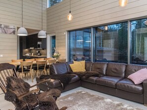 A modern living room with a leather sectional sofa, a dining area with wooden chairs, and a kitchen in the background. - Käkikello by Interhome (Mikkeli)