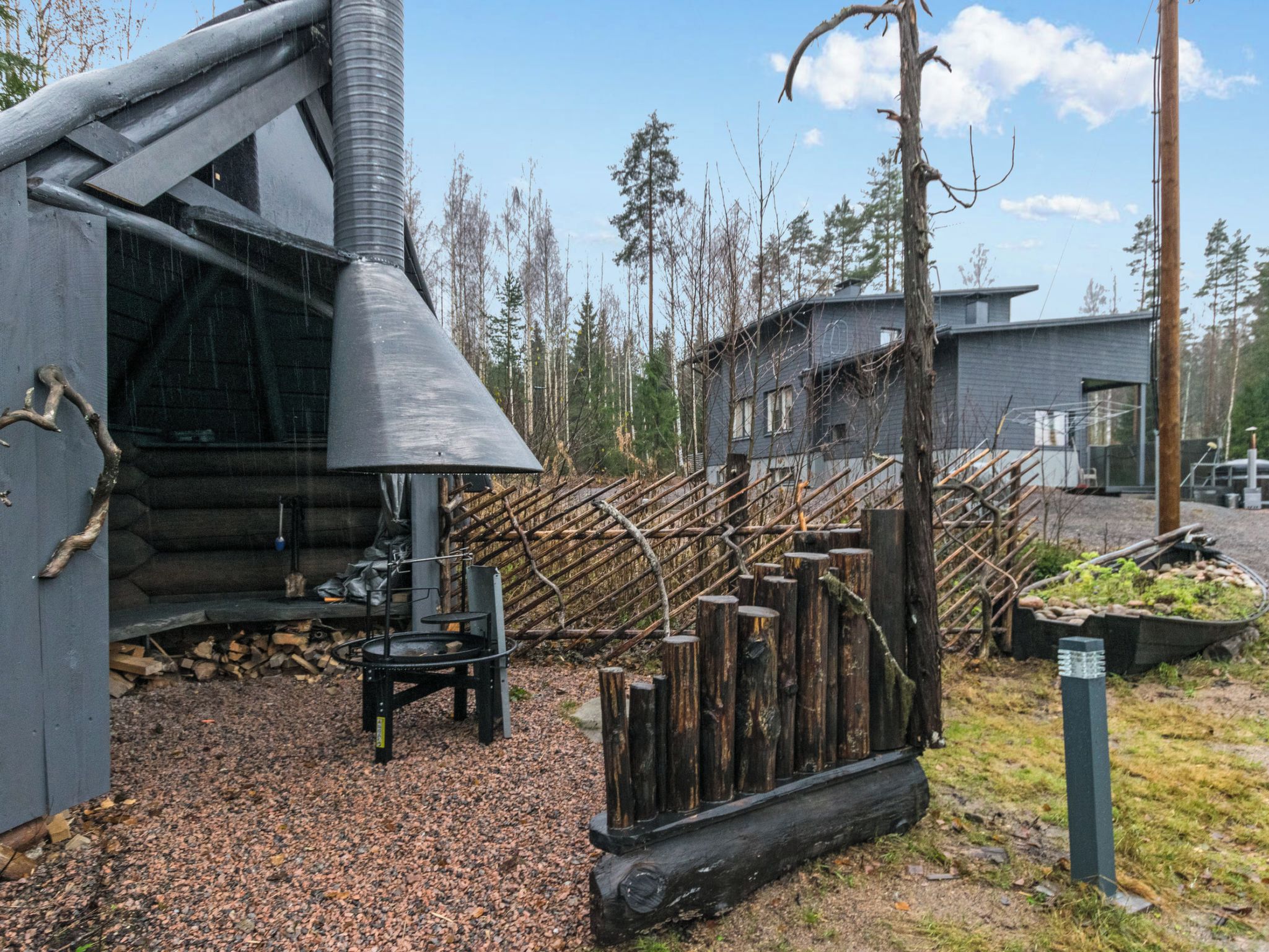 Una cabaña rústica con chimenea, una escalera de madera y zona de almacenamiento de troncos.