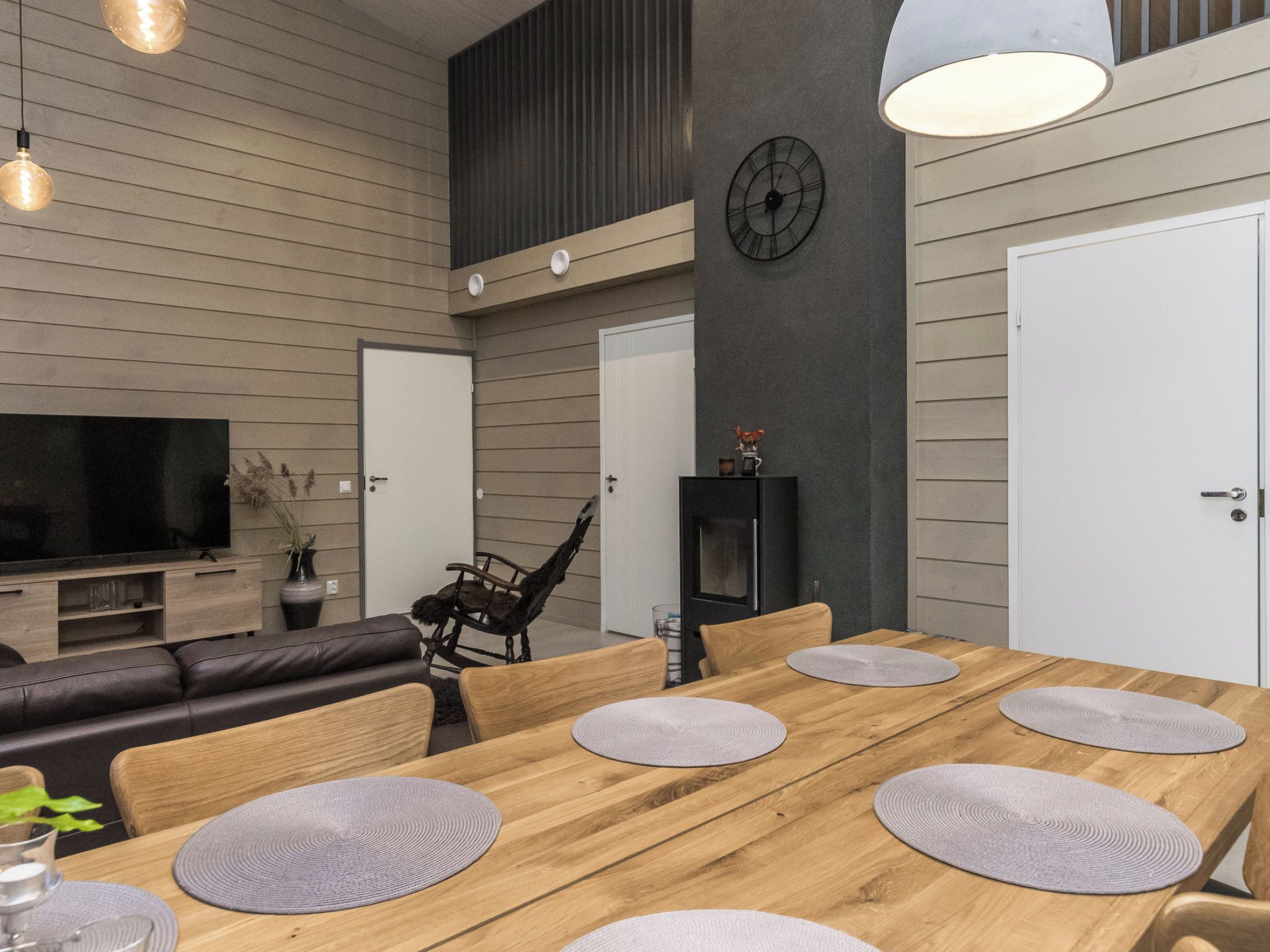 A modern dining area with a wooden table, grey placemats, and a black chair.