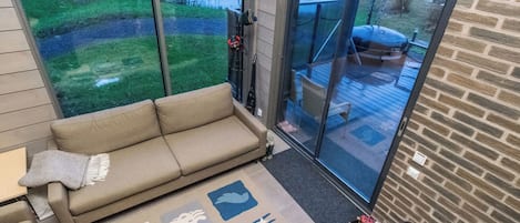 A modern interior with a sofa, a glass door leading to an outdoor deck, and a fireplace.