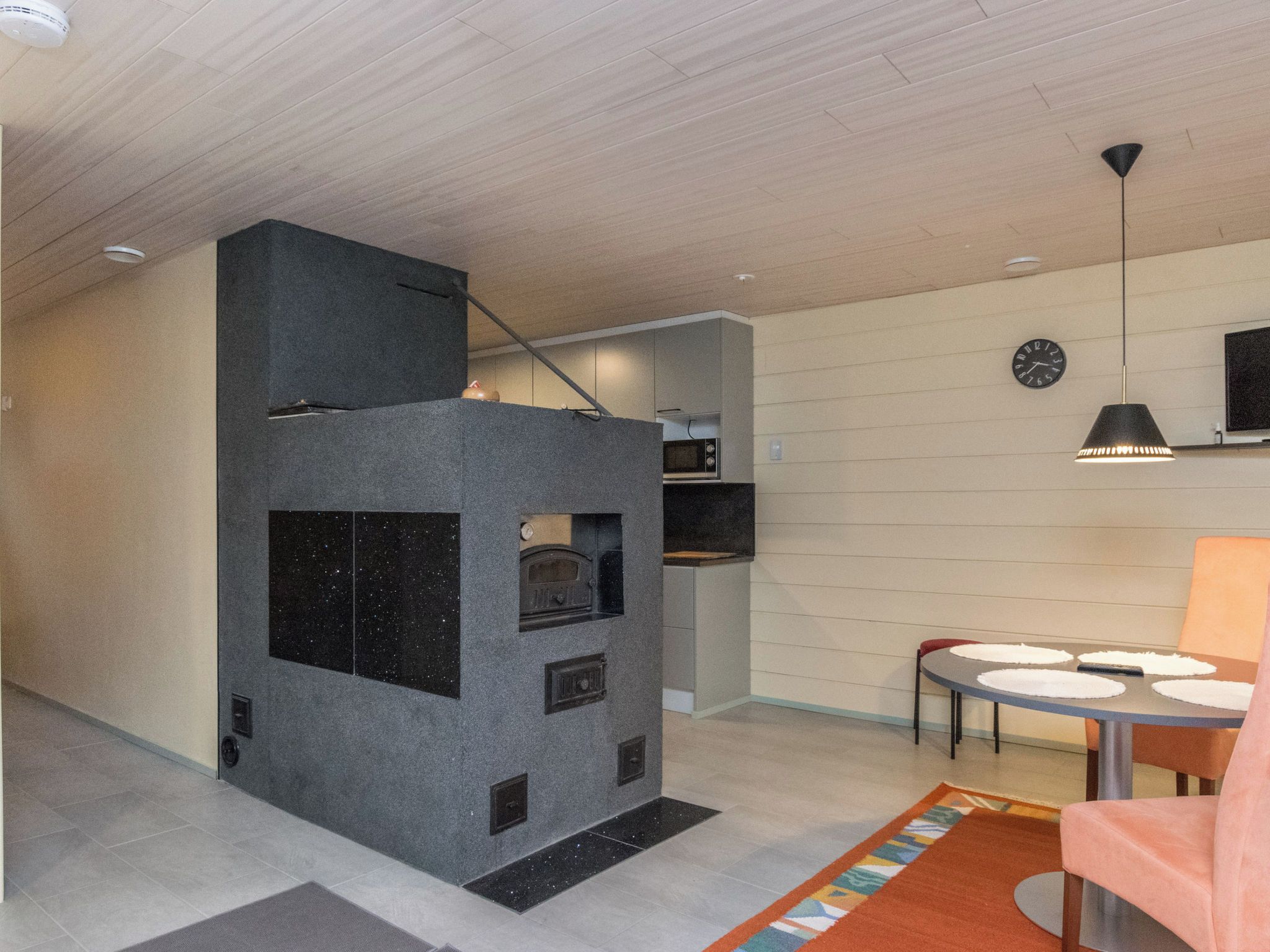 A modern kitchen with a built-in stove, a microwave, and a dining area with a table and chairs.