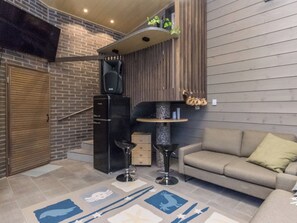 A modern interior with a sofa, two bar stools, a small table, a speaker, and a decorative wall. - Käkikello by Interhome (Mikkeli)