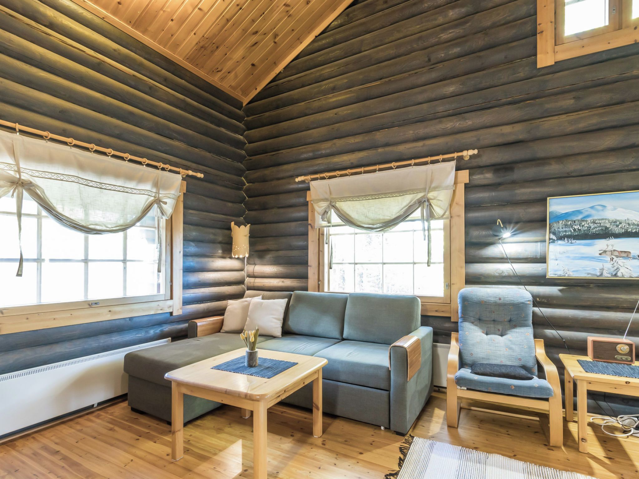Ein Holzblockhaus-Interieur mit einer Couch, einem Sessel und einem kleinen Tisch mit einer Vase.