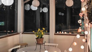 Un coin repas avec une table, des chaises, un panier de fleurs et des lanternes en papier suspendues.