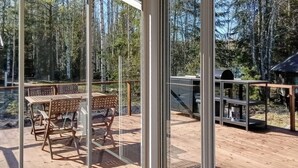 Une terrasse en bois avec une porte vitrée donnant sur un espace extérieur aménagé avec une table et des chaises.