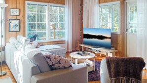 Un salon confortable avec un canapé, une télévision et de grandes fenêtres.