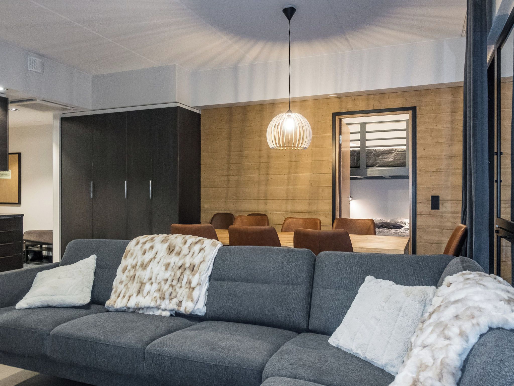 Un salon moderne avec un canapé gris, une table à manger en bois et des chaises.