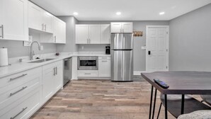 Une cuisine moderne avec des armoires blanches, des appareils en acier inoxydable et un plancher en bois.