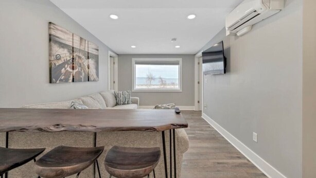 Un salon moderne avec une grande table à manger en bois, un canapé et un téléviseur fixé au mur.