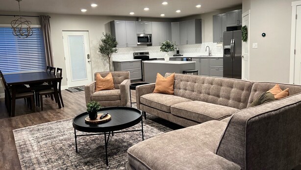 A modern living room with a sofa, armchairs, a coffee table, and a dining table. - Cozy Cascade Nook - 2 bedroom basement apartment (OREM)