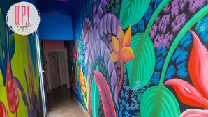 A brightly colored hallway with a vibrant mural of tropical flowers and foliage.