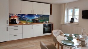 A modern kitchen with white cabinets, a wooden countertop, and a large window. - Ferienwohnung 4 mit Balkon (Berchtesgaden)