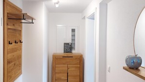 A hallway with a wooden bench, a cabinet with a chalkboard sign, and a mirror on the wall. - Ferienwohnung 4 mit Balkon (Berchtesgaden)
