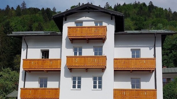 A multi-story building with balconies, a stone facade, and a mountainous backdrop. - Ferienwohnung 4 mit Balkon (Berchtesgaden)