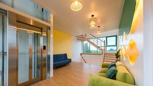 Een modern interieur met een trap, een groene bank en een blauwe slaapbank.