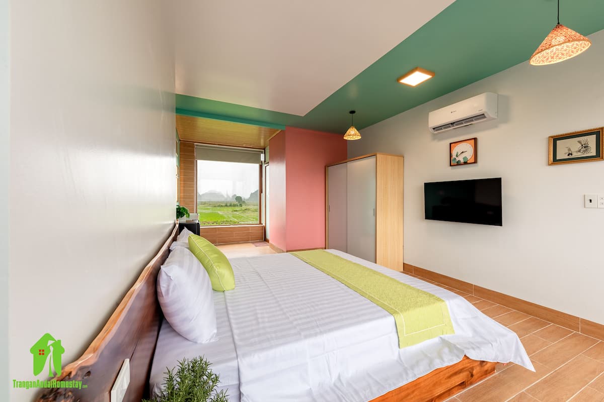 Een slaapkamer met een bed, een televisie en een raam met uitzicht.