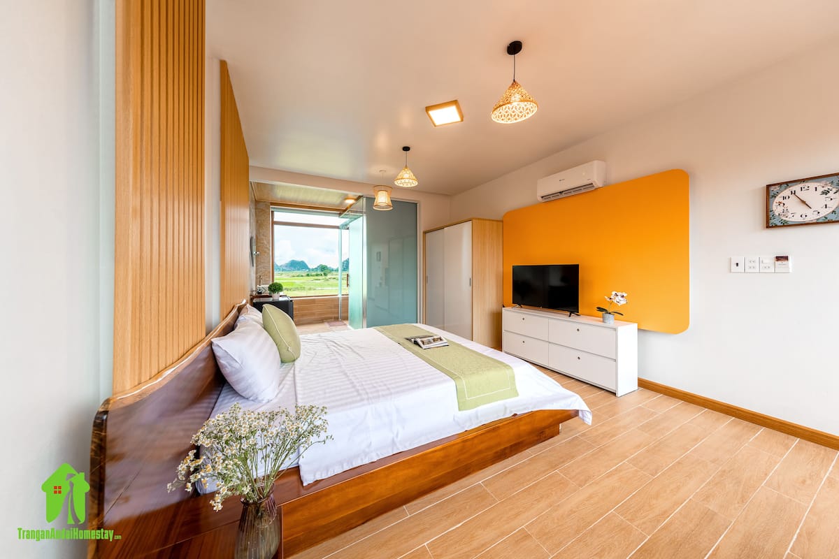 Een slaapkamer met een bed, nachtkastje, televisie en uitzicht op de omgeving.