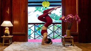 Yoga houding op een mat in een kamer met houten wanden, een lamp en een vaas met bloemen.