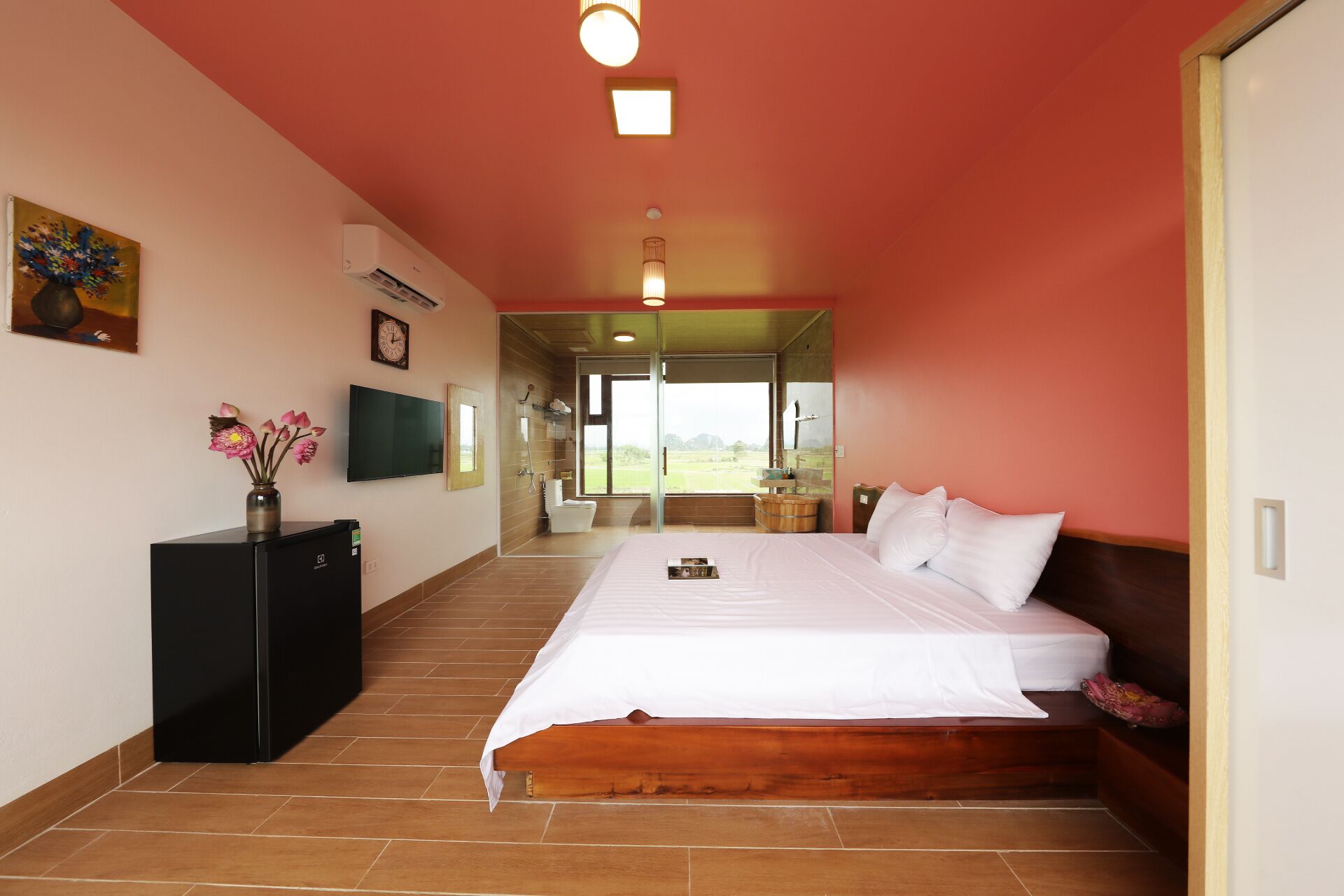 Een ruime slaapkamer met een groot bed, een televisie en uitzicht op de omgeving.