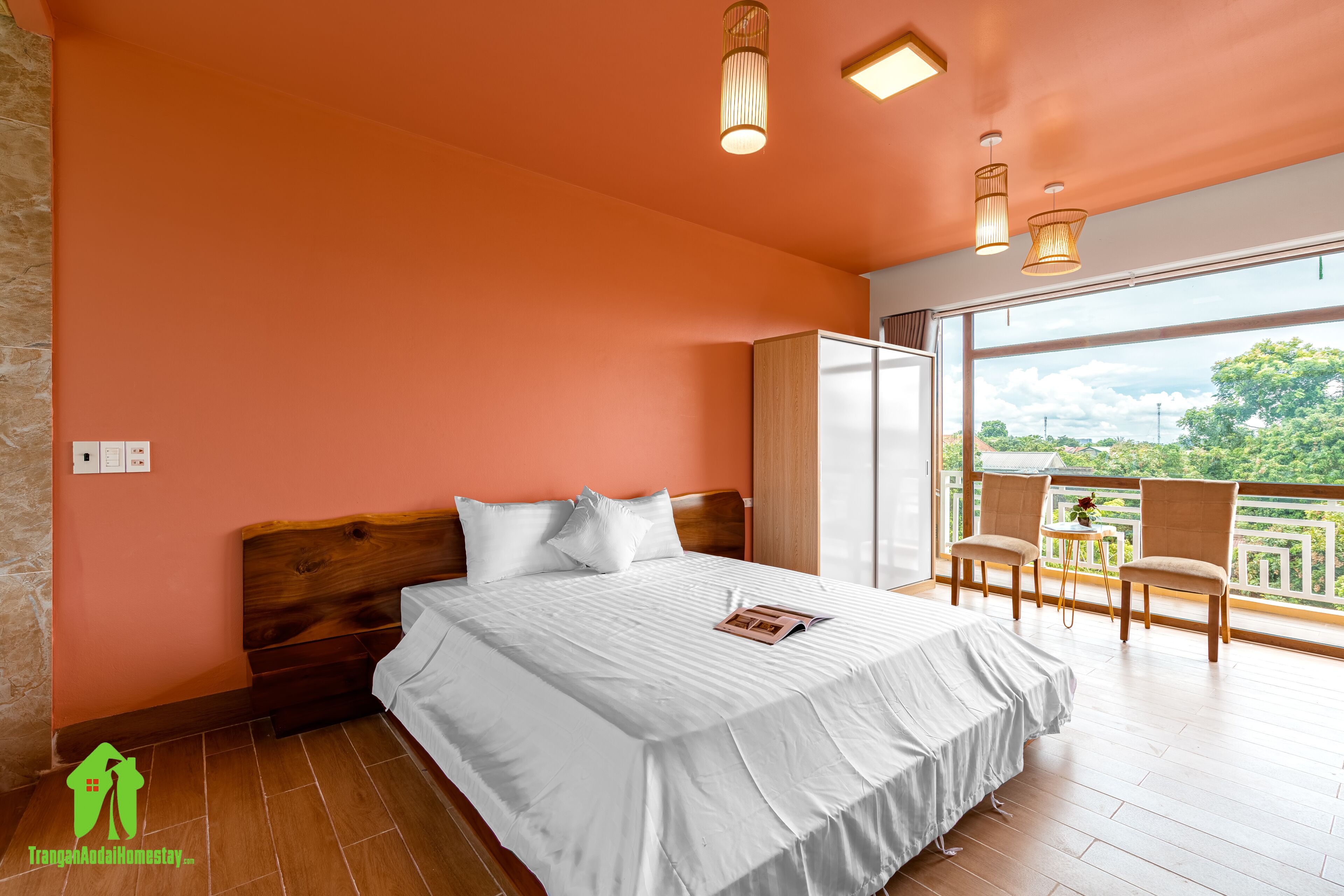 Ein Schlafzimmer mit einem großen Bett, einem hölzernen Kopfteil und einem Balkon mit Sitzgelegenheiten.