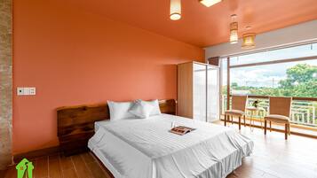 Ein Schlafzimmer mit einem großen Bett, einem hölzernen Kopfteil und einem Balkon mit Sitzgelegenheiten.
