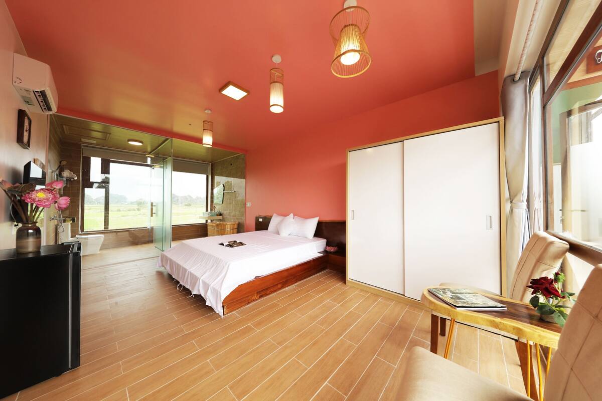 Een slaapkamer met een bed, nachtkastje en uitzicht door een glazen deur.