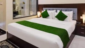 A hotel room with a large bed, a nightstand, a mirror, and a window.